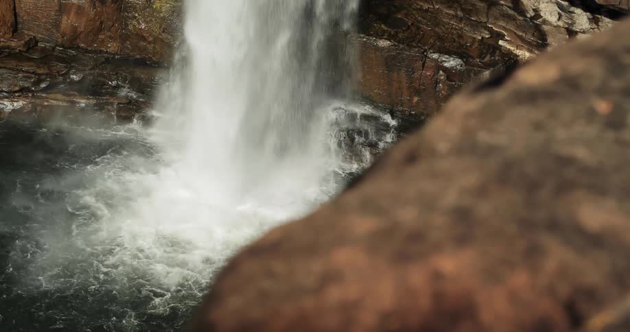 Water from the waterfall splashes as it hits the rocks