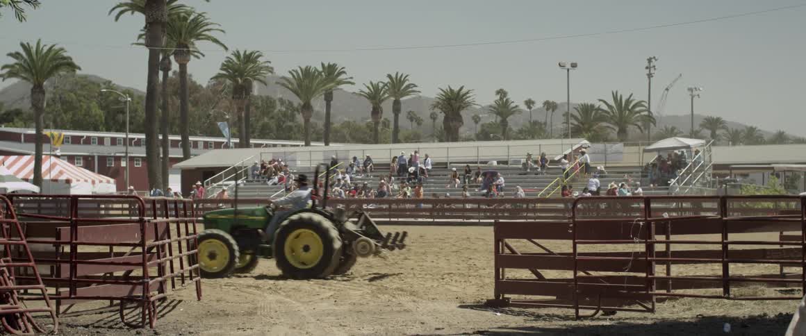 A man rides a tractor through a stadium