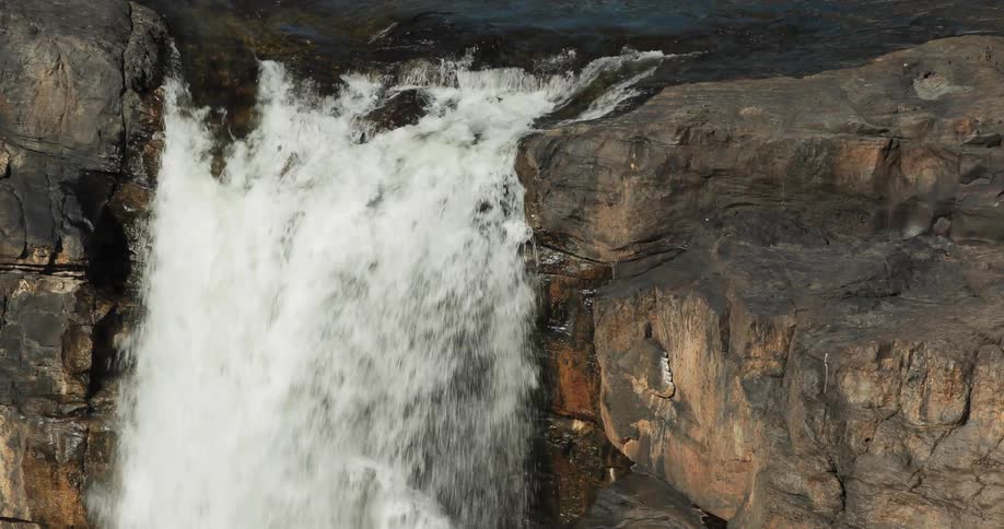 Water falls off the side of a stone cliff