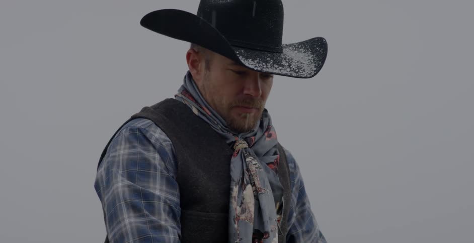 Man with a cowboy hat outside in the snow