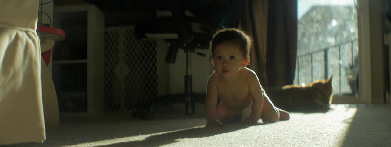 A baby is crawling and exploring on a living room floor during the day