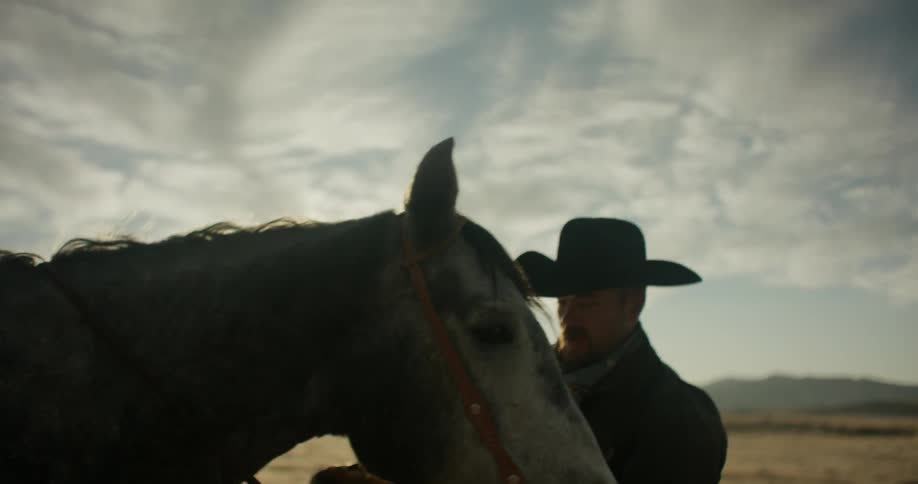 Cowboy checks his horse's equipment