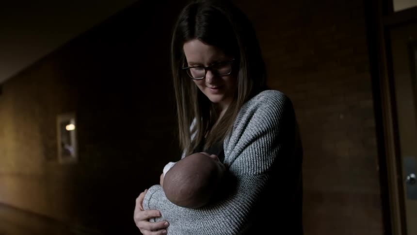 A woman looks lovingly at a newborn in her arms