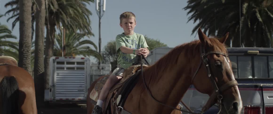 A young boy is sitting in a saddle on a horse
