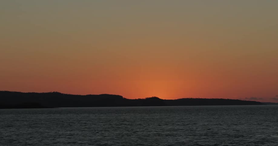 Sun set behind island and flowing water