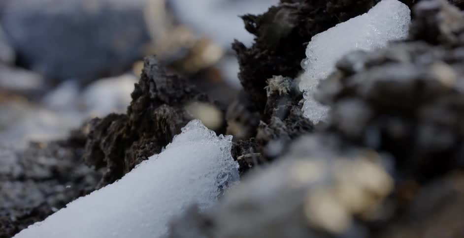 Snow falls on the rocky ground