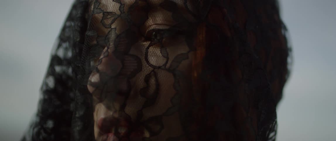 A woman wears a black lace veil over her face