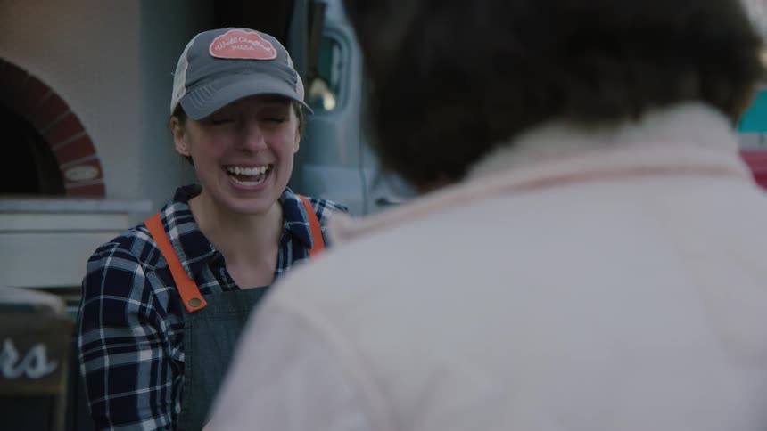 A woman smiles while speaking to a person