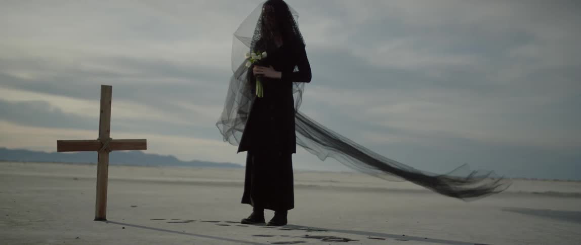 A woman holds flowers near a grave