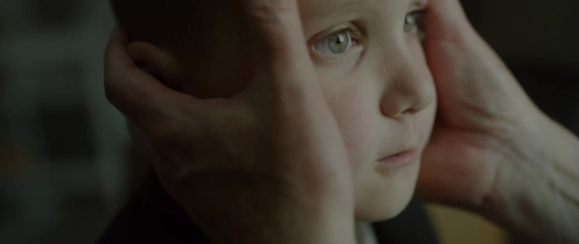 Large hands hold a child's head making him look up