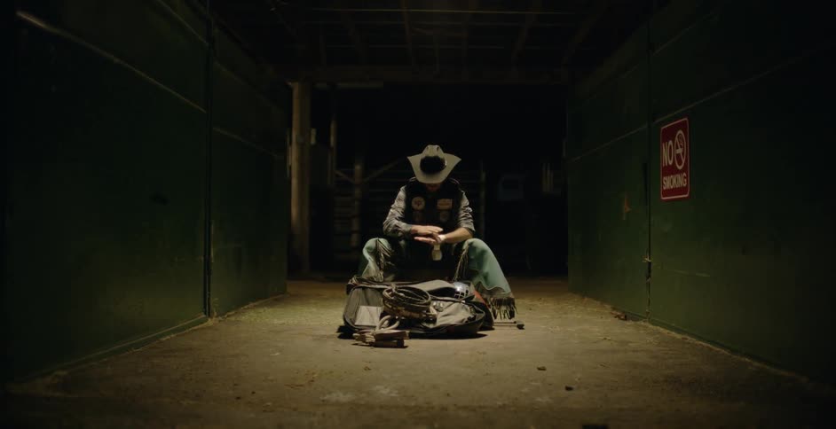 A man is sitting in a dark hall using bandages