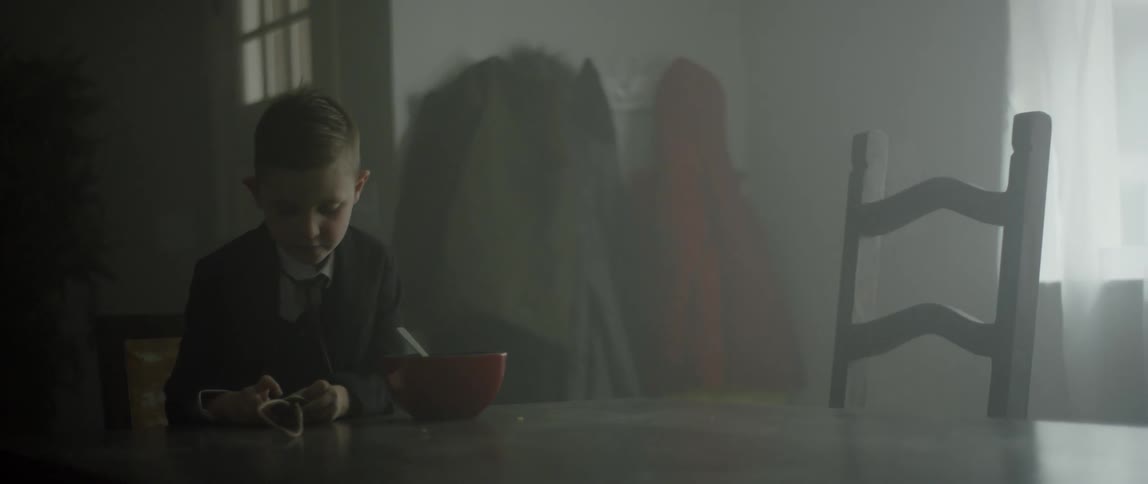 A young boy sits at a table with a bowl