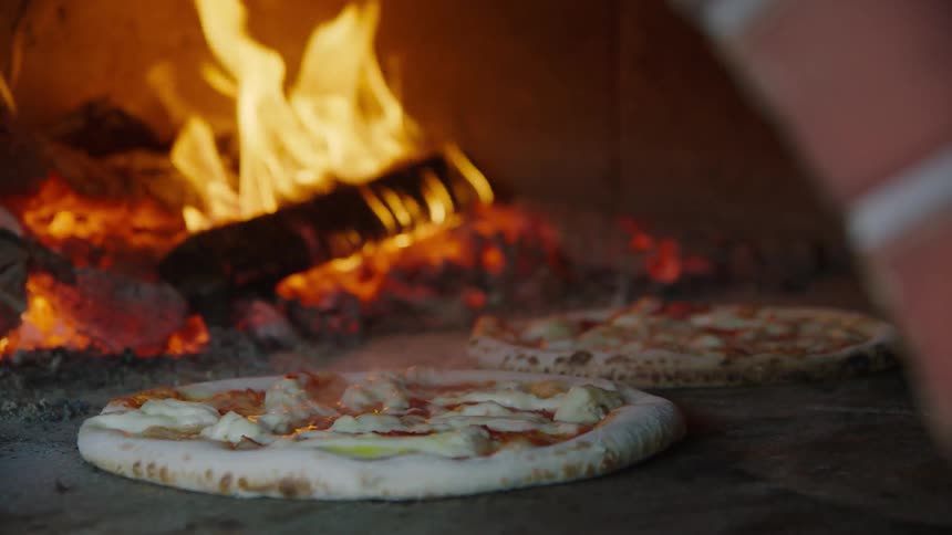 Pizza is cooking near a fire