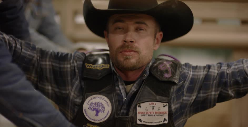 A rodeo cowboy waiting for the starting bell shifts his position