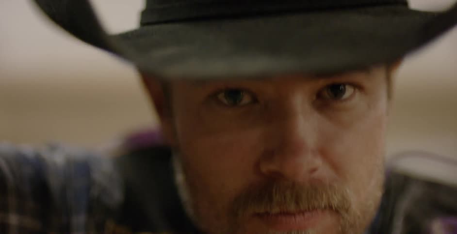 A cowboy looks up and nods his head