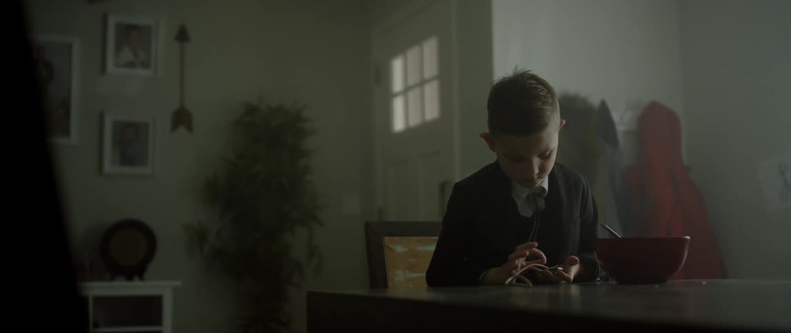 Child sitting at a table playing with a small object