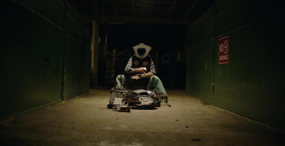 A cowboy sits in a pen wrapping his hands