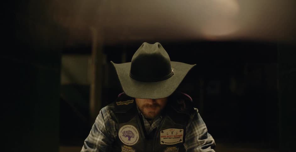 A cowboy is sitting indoors deep in thought