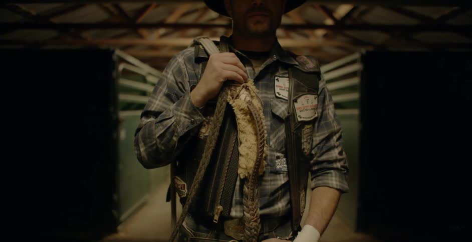 A cowboy stands with ropes and a harness