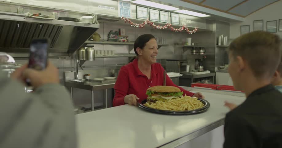 A woman serves up a large platter of food in a diner