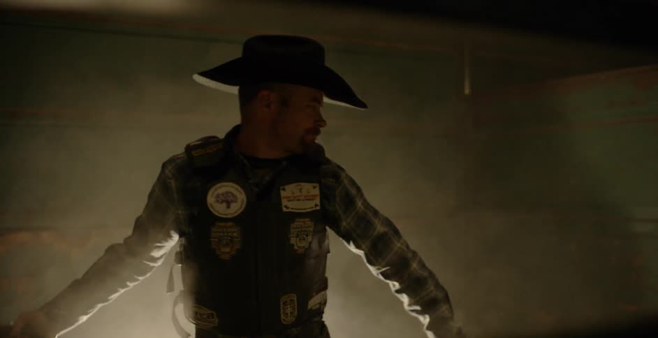 A cowboy throws ropes inside a metal pen