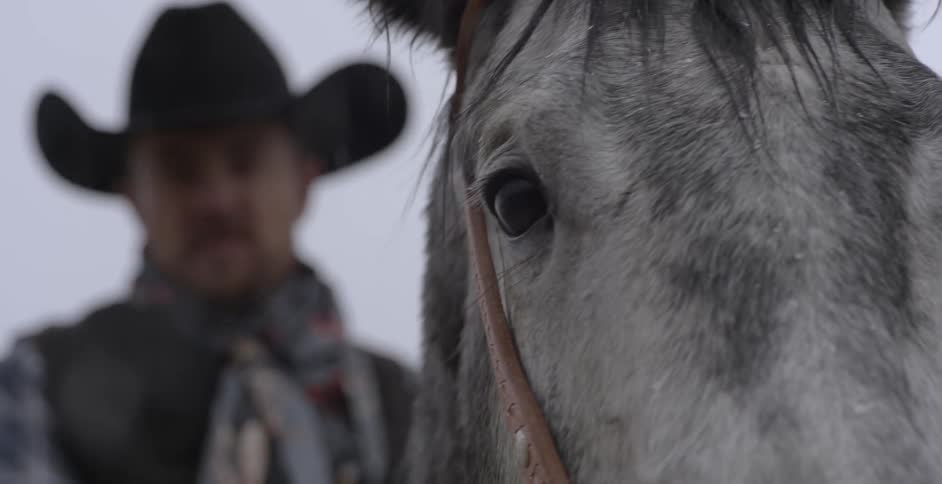 A cowboy rides a horse in a snowstorm