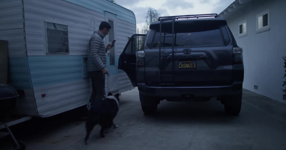 A man herds his child and dog into an suv