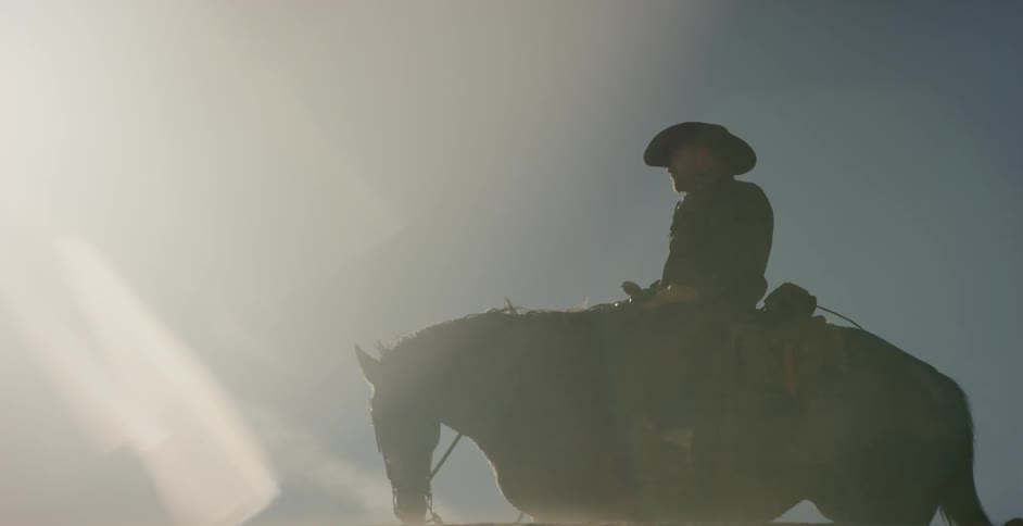 A man is riding a horse on a windy day