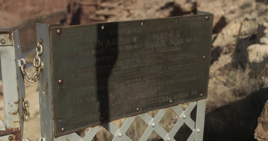 A bronze plaque on a white metal sign