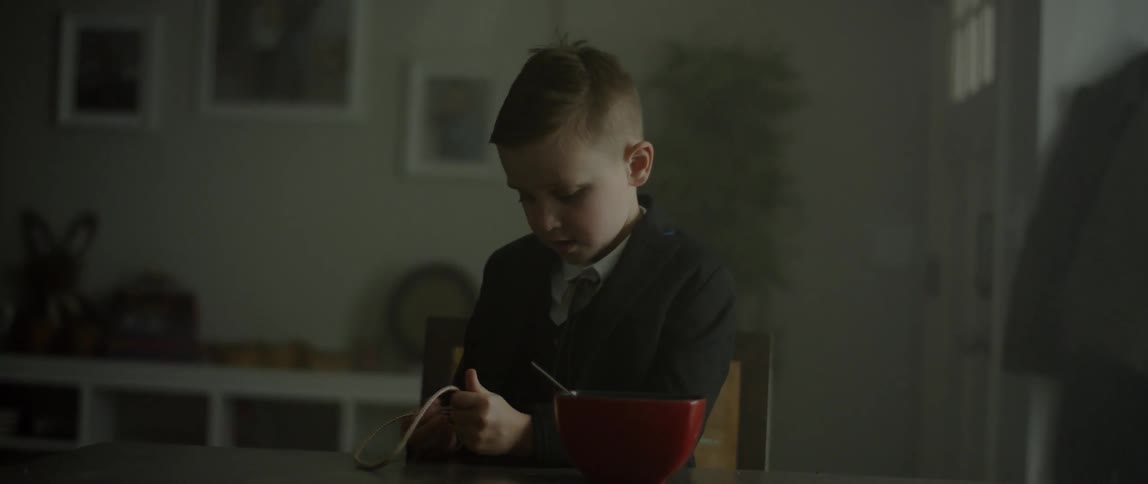 A boy plays with a rope while sitting at a table with a bowl of food