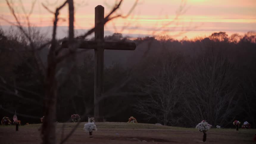 A tall wooden cross in a cemetery