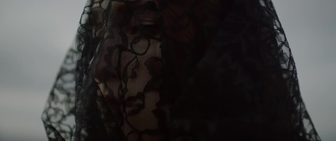 A woman wears a black lace veil over her face