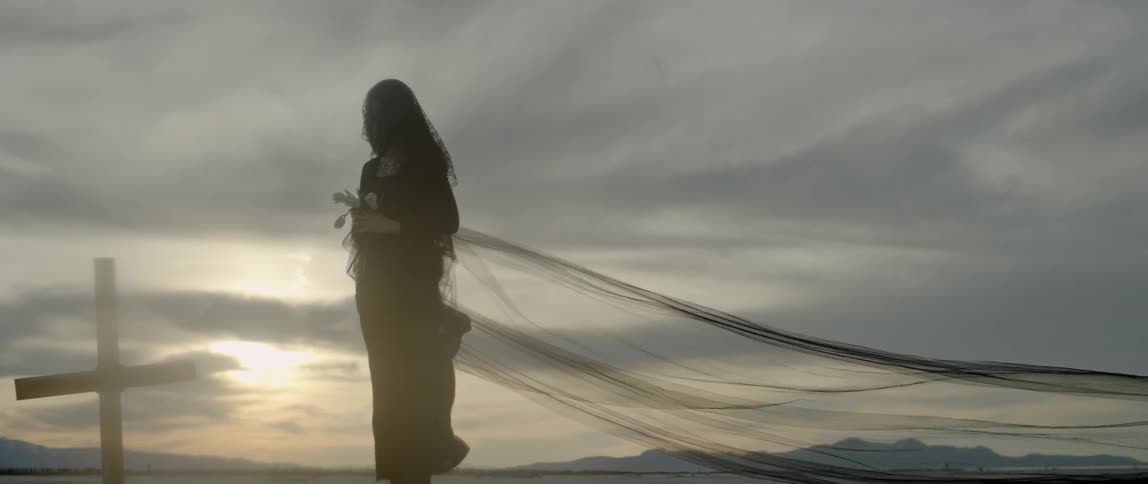 The wind blows the long black veil of a woman