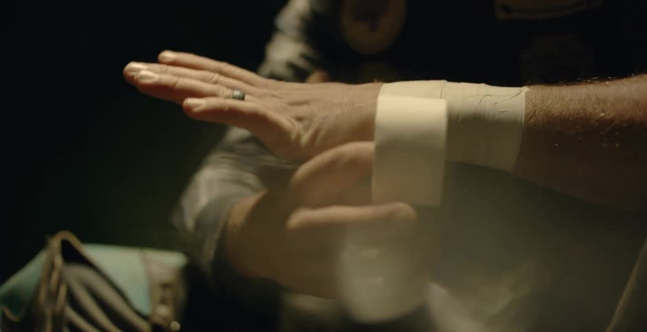 A rodeo cowboy is putting tape on his wrist