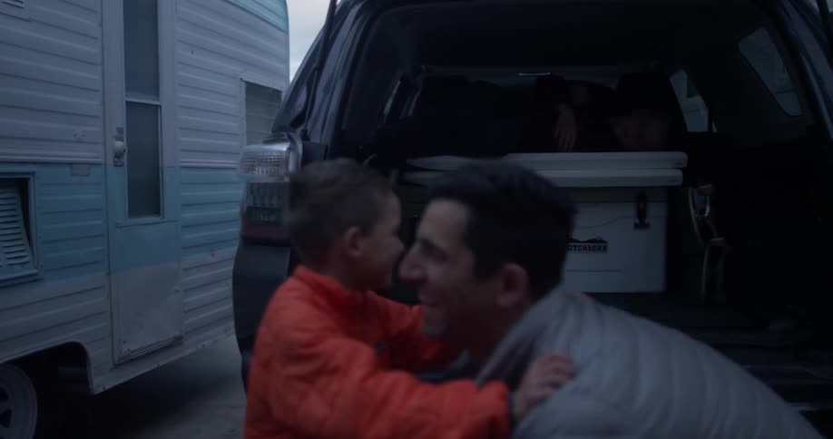 A man picks a boy up by the car