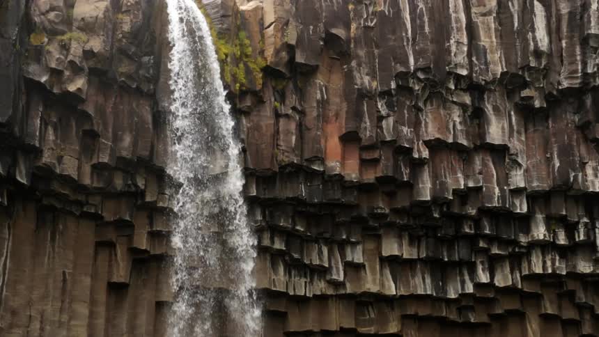 A waterfall flows over a rocky cliff