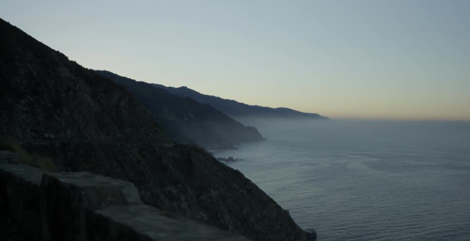 A stone barrier wall overlooks cliffs and the ocean