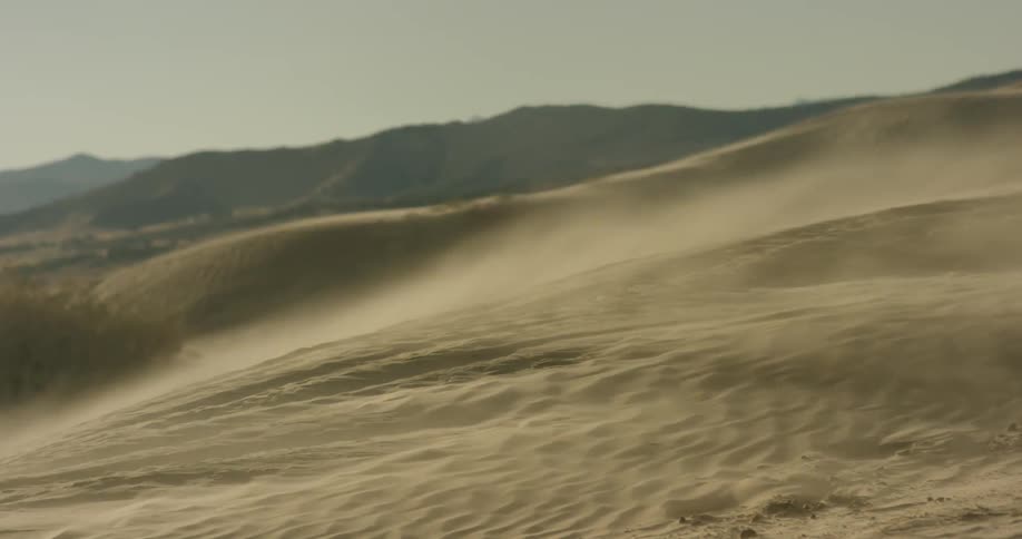 The wind is blowing the sand over the hills