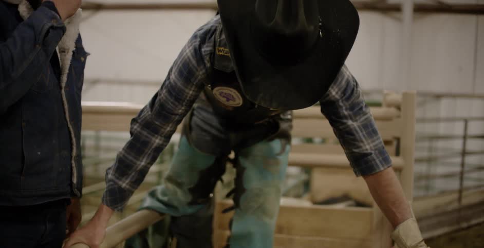 A cowboy crawls into a small pen