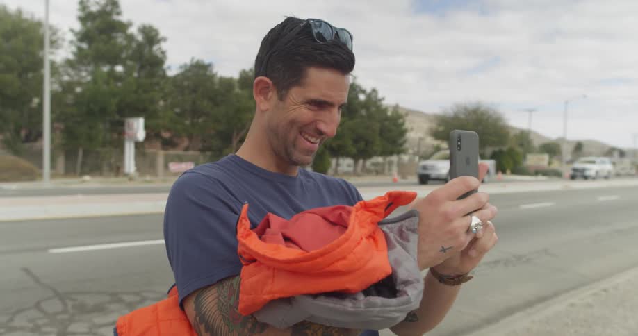 A man is smiling and talking as he looks into a cell phone