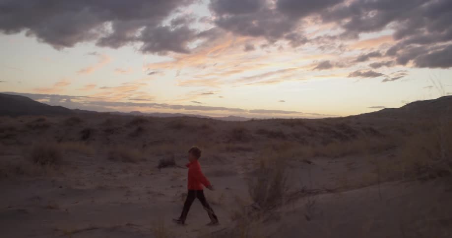 A child runs along a scrubby beach