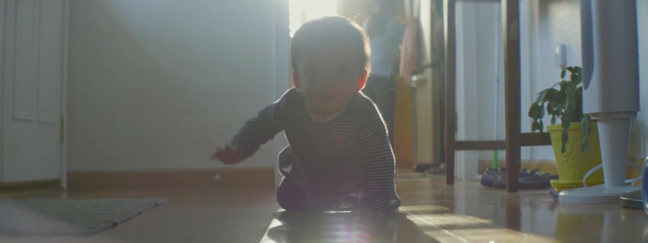 A baby is crawling and exploring on a living room floor during the day