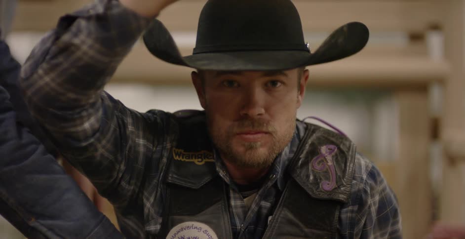 Man wearing cowboy hat looks up and nods his head