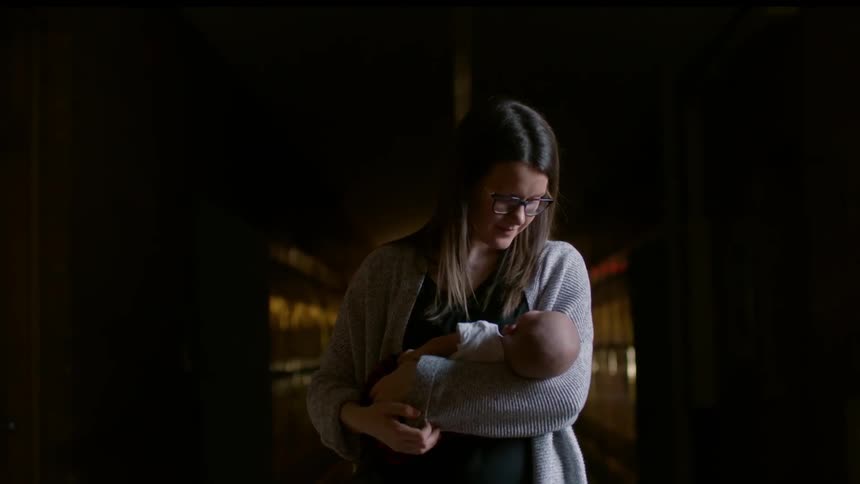 A woman holds an infant in a hallway