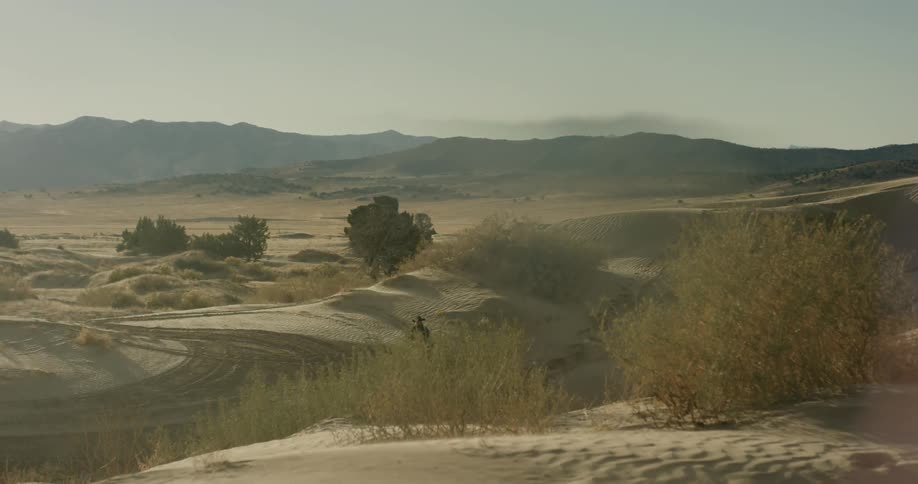 A man riding a horse through the desert sand and brush