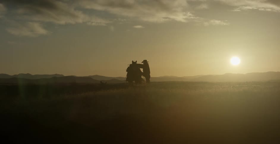 A man rides a horse towards the sunset