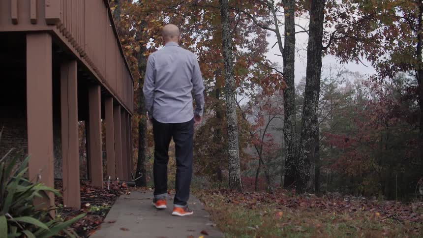 Man walking next to a balcony near trees