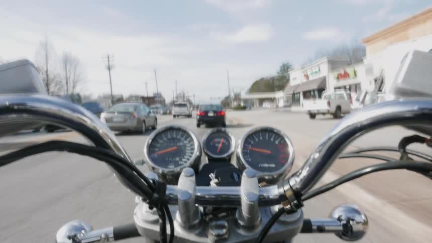 A time lapse of a motorcycle moving along in traffic through business and residential areas