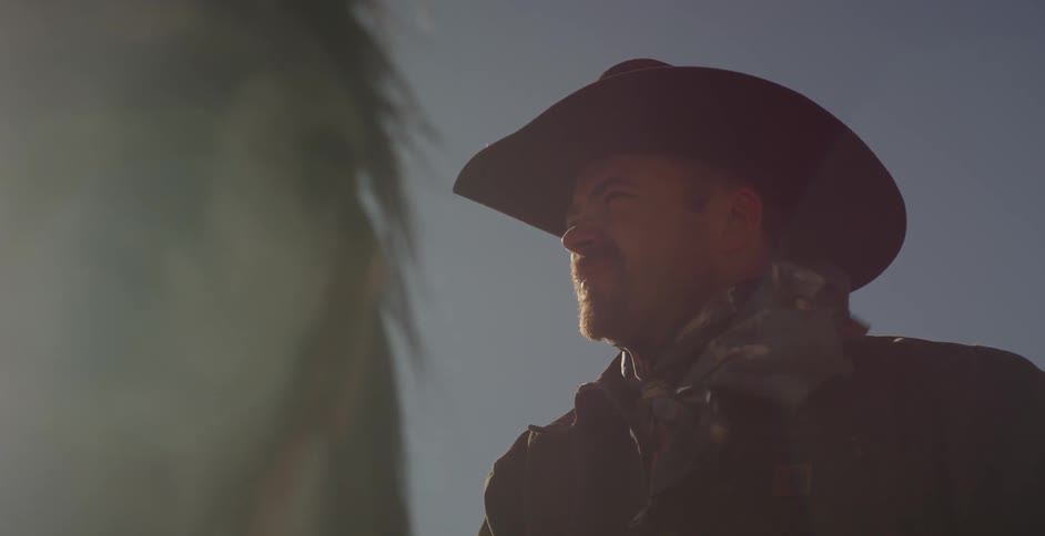 Sunlight shines down on a cowboy riding a horse