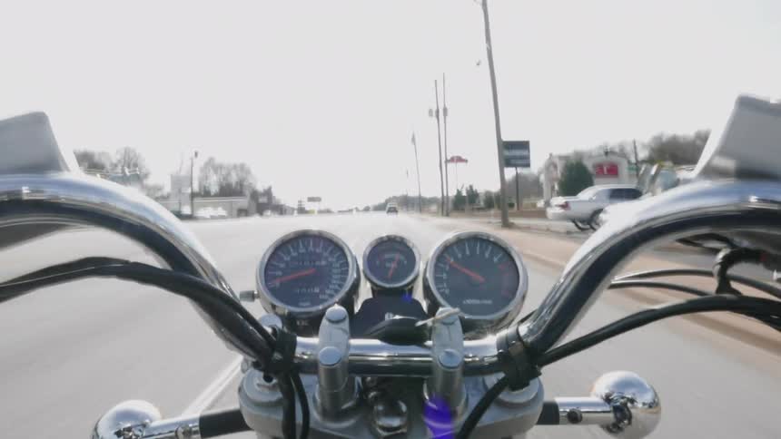 A person is riding a motorcycle through a small town during the day
